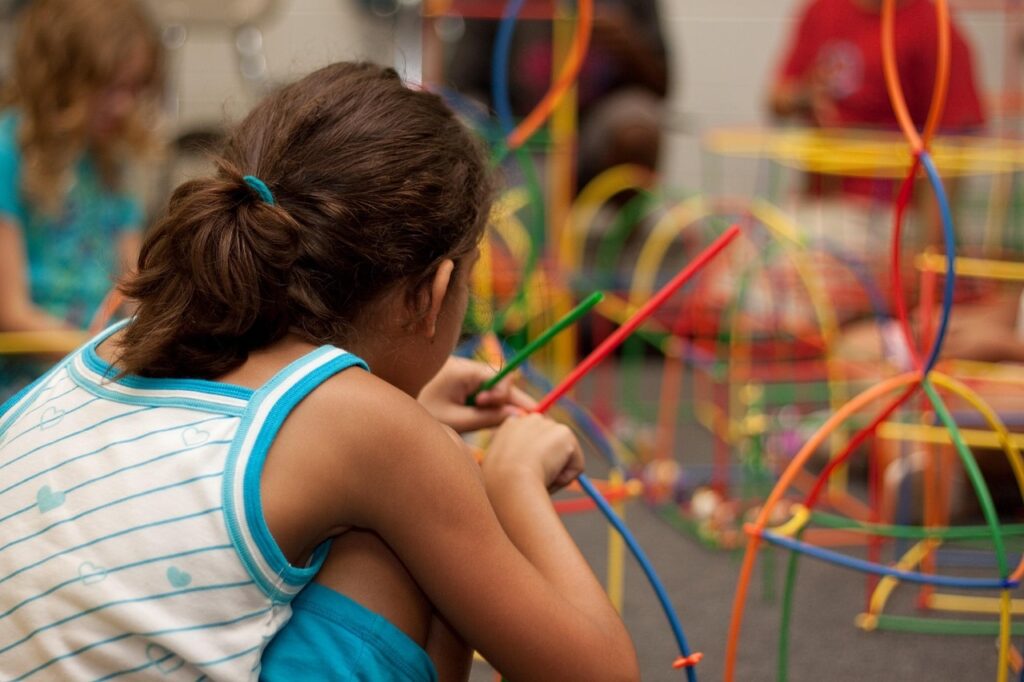 Imagen de una niña construyendo figuras geométricas con varillas de colores.